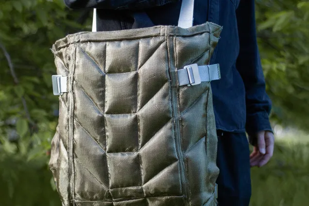 person holding a large bag with a quilted pattern