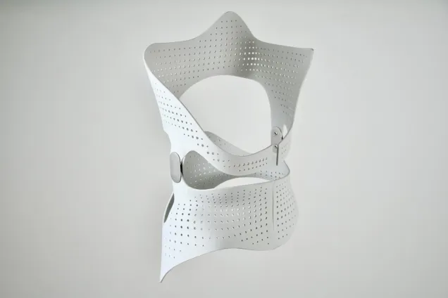 Perforated scoliosis brace with hinges, shown on neutral background. Photo.