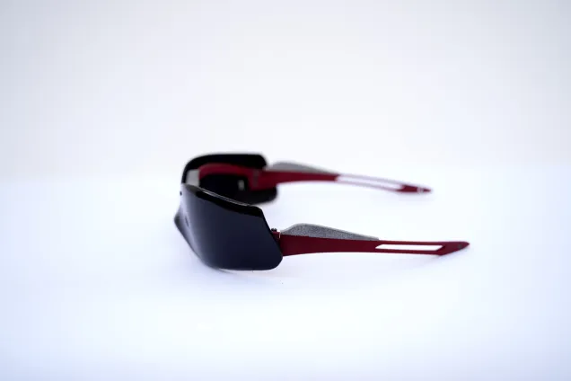 Eyewear featuring a seamless high-gloss black PETG lens mounted on a frame of burgundy and sandblasted grey Nylon. Photo. 