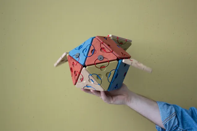 Fish built from triangles and squares with two eyes held up by a hand. Photo. 