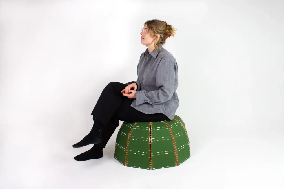 person sitting on a green tiled pouf