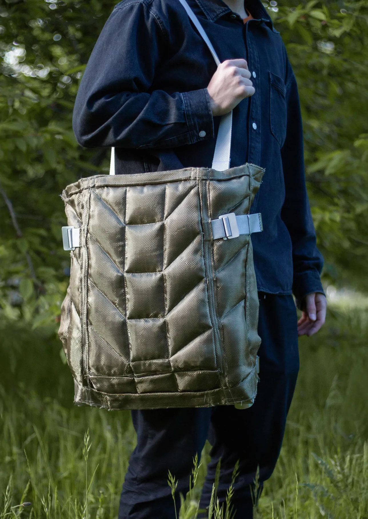 person holding a large bag with a quilted pattern