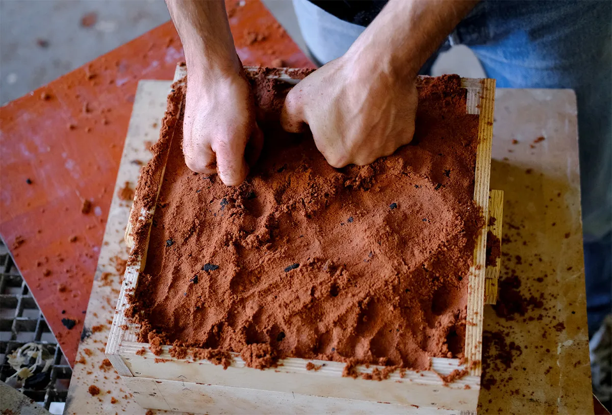 Packing red sand into a mold. Photo. 