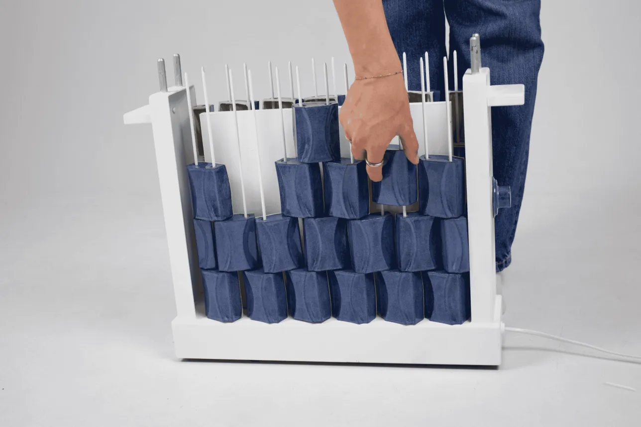 Stacking blue ceramic tiles onto vertical rods. Photo. 