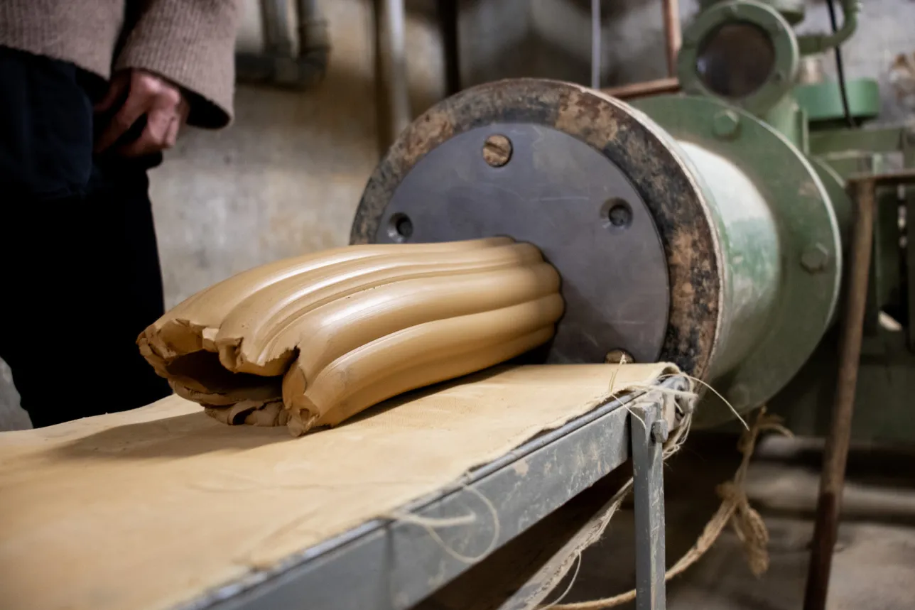 clay tube being extruded from a machine. Photo. 