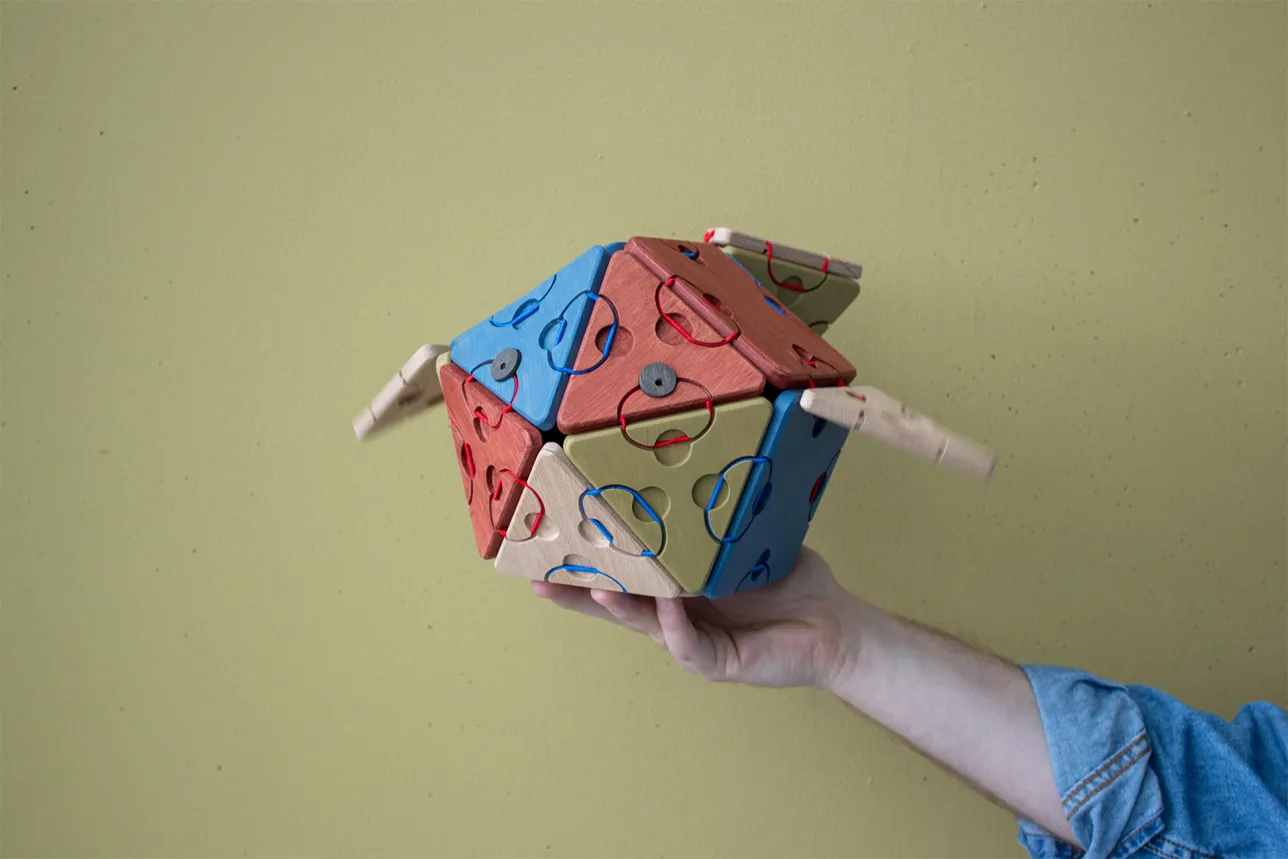 Fish built from triangles and squares with two eyes held up by a hand. Photo. 