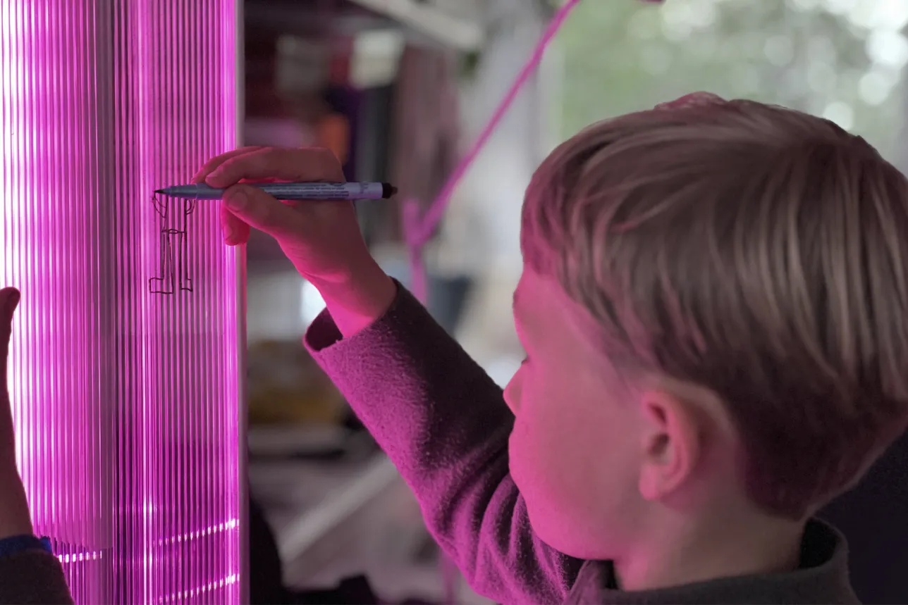 Child drawing on the screen which has a purple color. Photo. 
