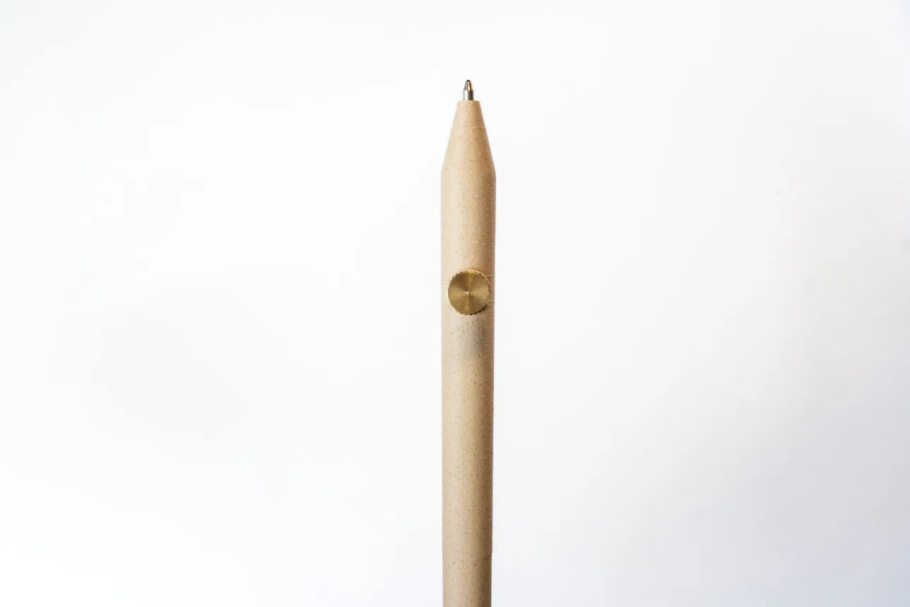 A beige pen with a metallic side button stands vertically against a plain white background, emphasizing its minimalist design.